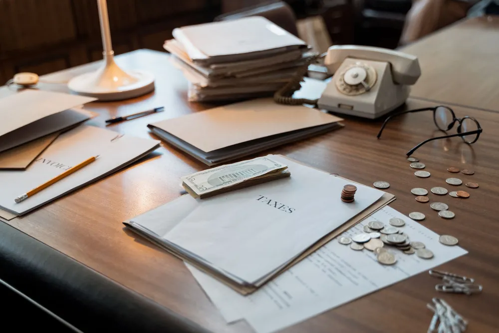 Un bureau organisé avec documents financiers, pièces de monnaie et lunettes