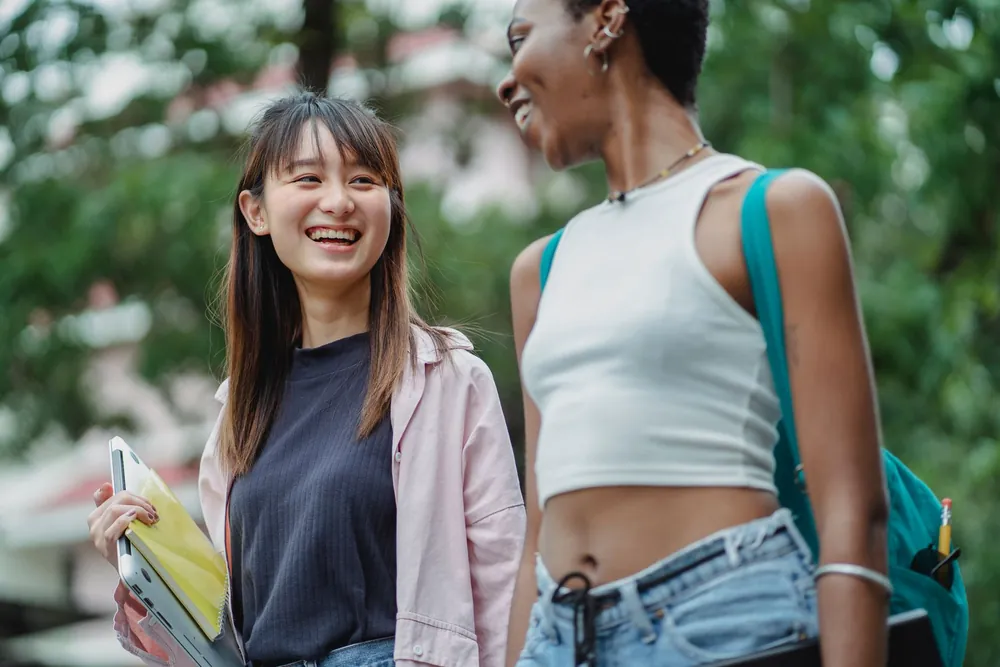 Étudiantes échangeant joyeusement dans un parc pendant leur séjour Erasmus