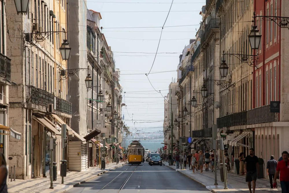 Rue animée de Lisbonne avec architecture historique et tramway jaune emblématique