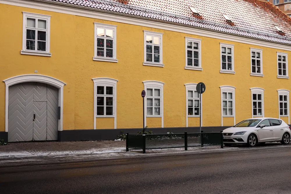 Bâtiment jaune au toit enneigé dans une rue de Malmö