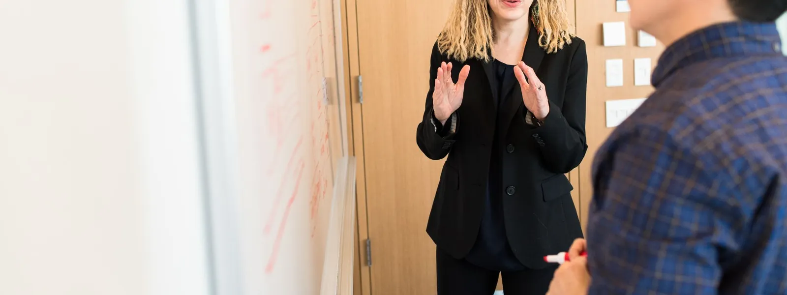 Collègues échangeant devant un tableau blanc dans un bureau anglophone